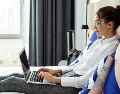 Beautiful young businesswoman working with her laptop lying on b