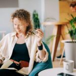 Woman puts on glasses and writes in paper notebook